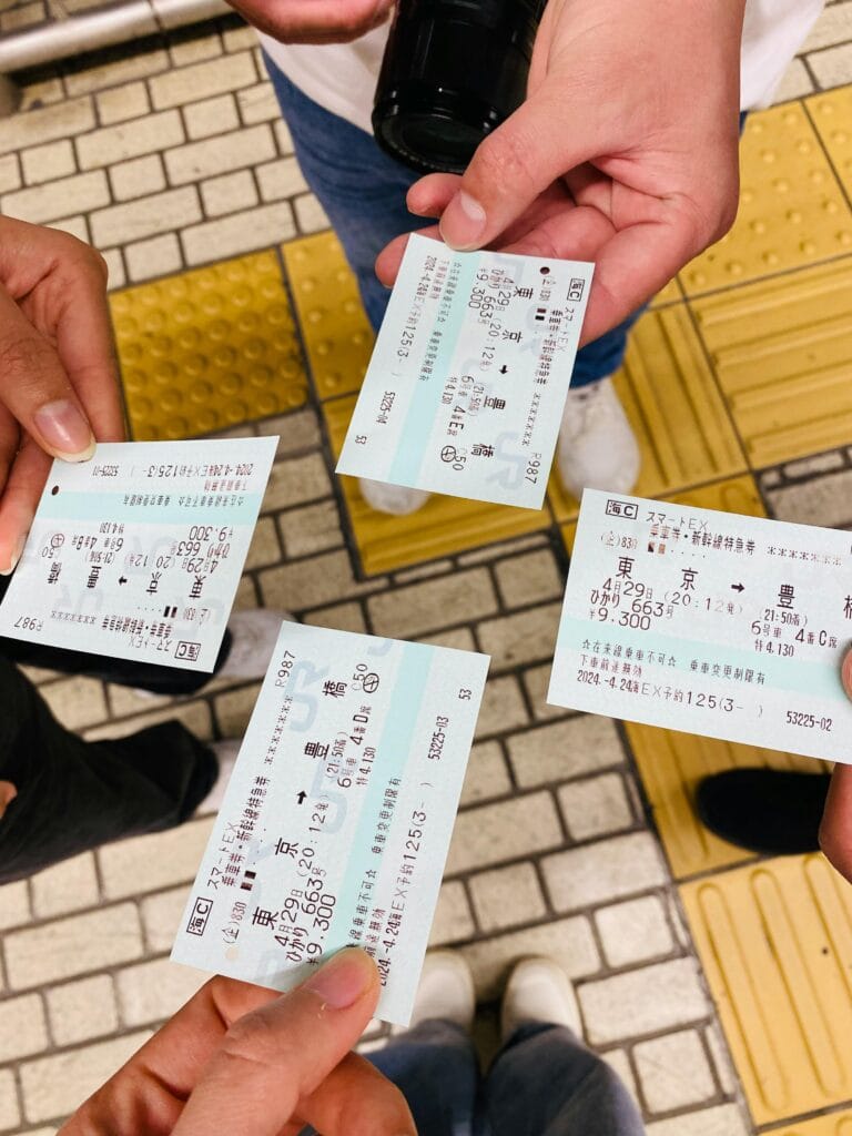 Four people holding train tickets at a Tokyo station, capturing a moment of travel.